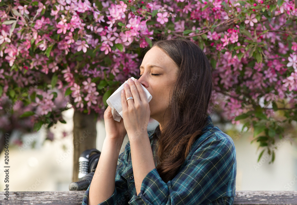 Woman sneezing because of spring pollen allergy Woman sneezing because of spring pollen allergy