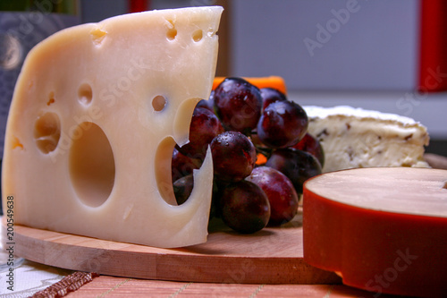 Still life Roquefort, swees cheese and red grapes on wooden plate photo