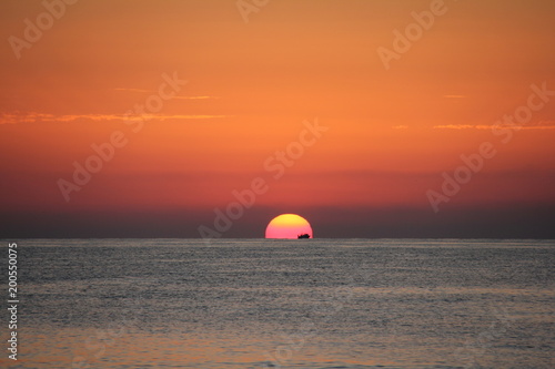 Fototapeta Naklejka Na Ścianę i Meble -  Sunrise in the sea with a cargo boat