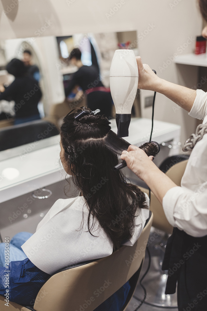 Female hairdresser making hairstyle to young woman in hair salon Female hairdresser making hairstyle to young woman in hair salon