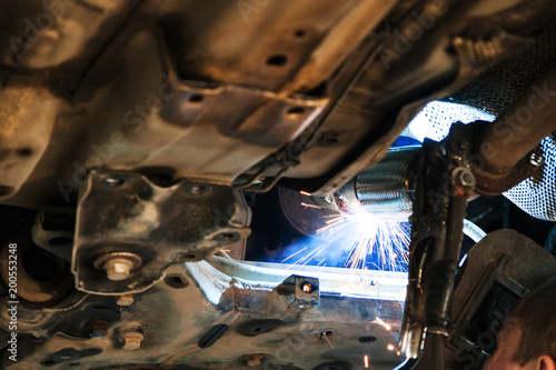 Obraz na plátne welder welds silencer on car by argon welding