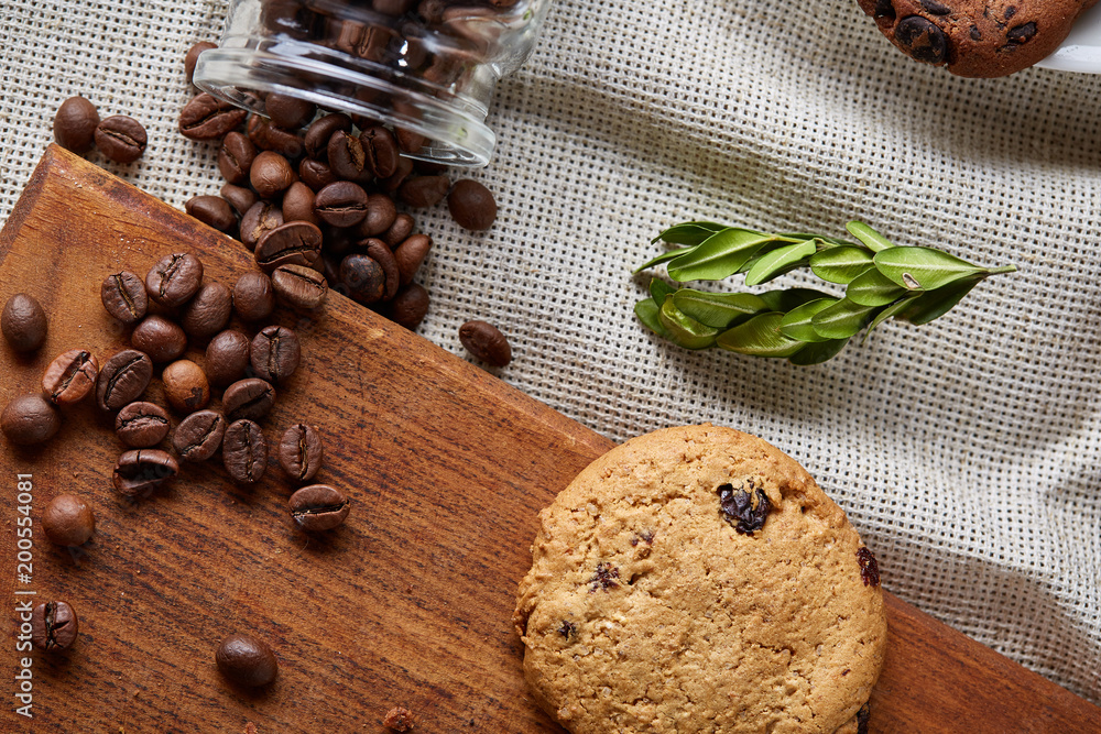 Roasted coffee beans get out of overturned glass jar on homespun tablecloth, selective focus, side view Roasted coffee beans get out of overturned glass jar on homespun tablecloth, selective focus, side view