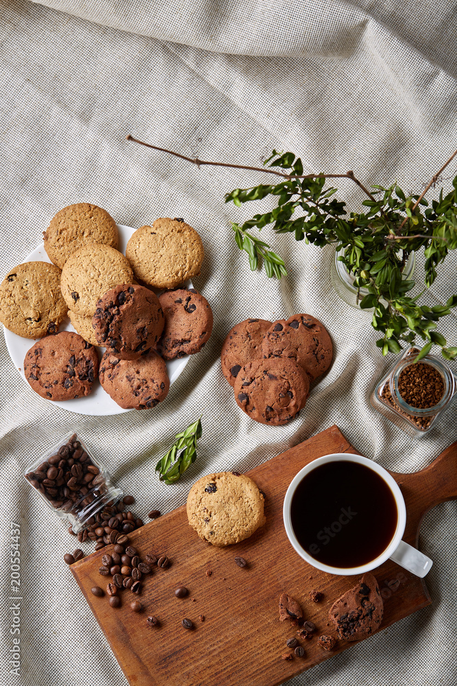 Coffee cup, jar with coffee beans, cookies over rustic background, selective focus, close-up, top view