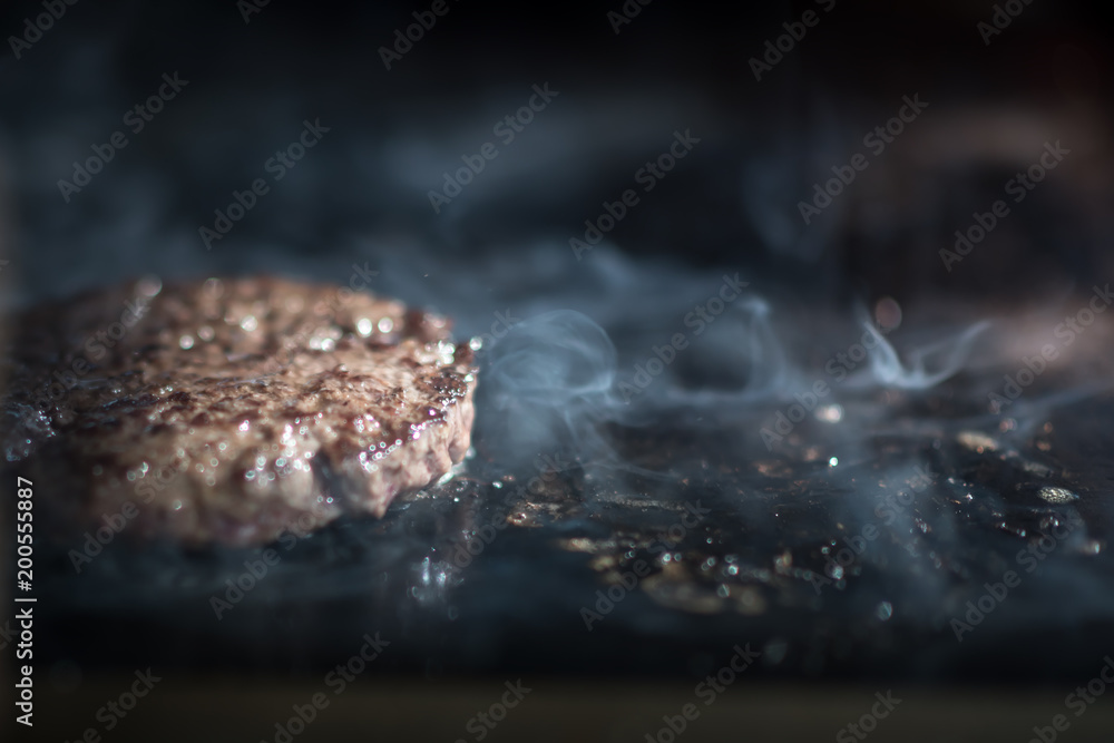 Hamburger cutlet frying on pan.Natural meet loaf pieces cooking in the kitchen.Burger sandwich meat being cooked with a lot of white smoke from a fat and oil. Hamburger cutlet frying on pan.Natural meet loaf pieces cooking in the kitchen.Burger sandwich meat being cooked with a lot of white smoke from a fat and oil.