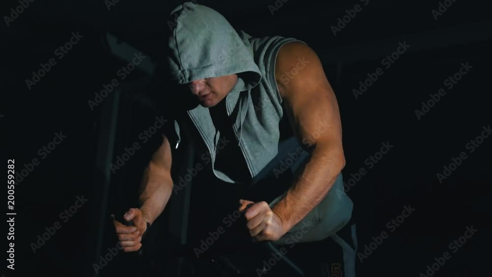 strong bodybuilder doing exercises on an exercise bike against