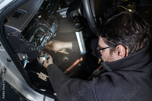 Electrician working into a car / Specialist installs alarm system in a car