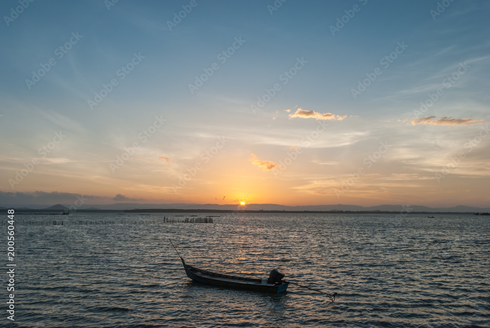 sunrise on the beach with wooden boat on the sea.