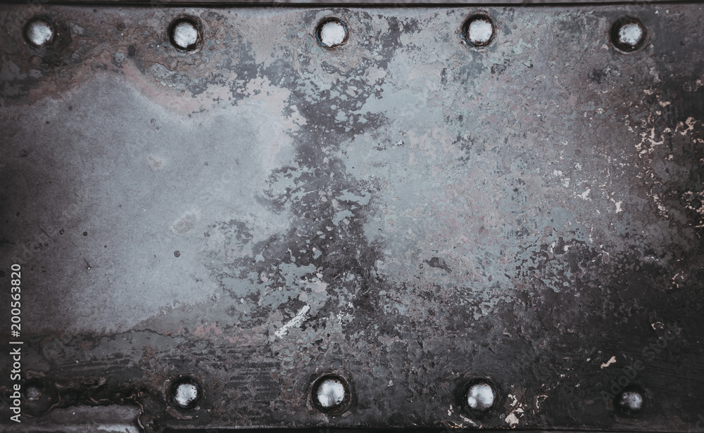 Metallic background painted with multicolored paint with large old rivets
