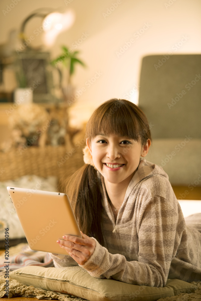 床に寝転びタブレットPCを操作する女性 床に寝転びタブレットPCを操作する女性