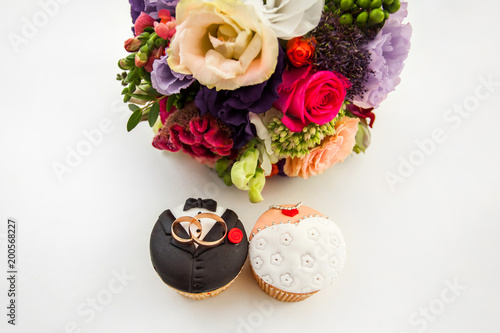 Bride and groom cupcakes with engagement rings on top. photo