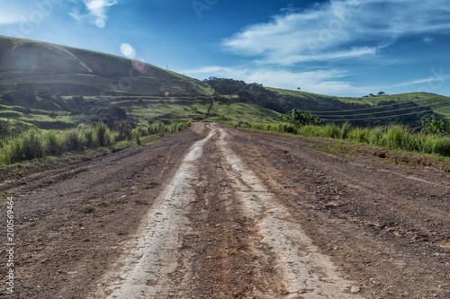 Mud road with tire marks runs through green valley in Malanje. Angola. Africa.