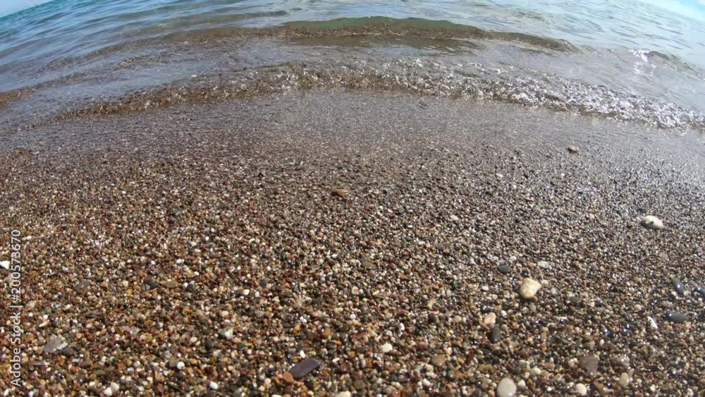 Waves breaking on the pebbles close up. Sea surf. Waves runs on coastal pebble. summer day sea and coast holiday concept Waves breaking on the pebbles close up. Sea surf. Waves runs on coastal pebble. summer day sea and coast holiday concept