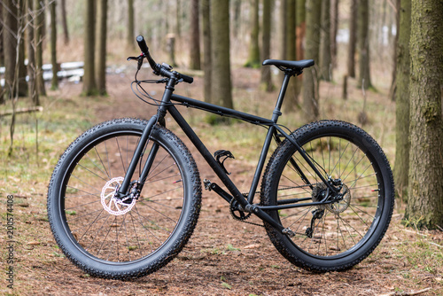 Big black bicycle with big wheels in the forest
