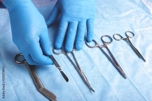 Detail shot of sterilized surgery instruments with a hand grabbing a tool , photo