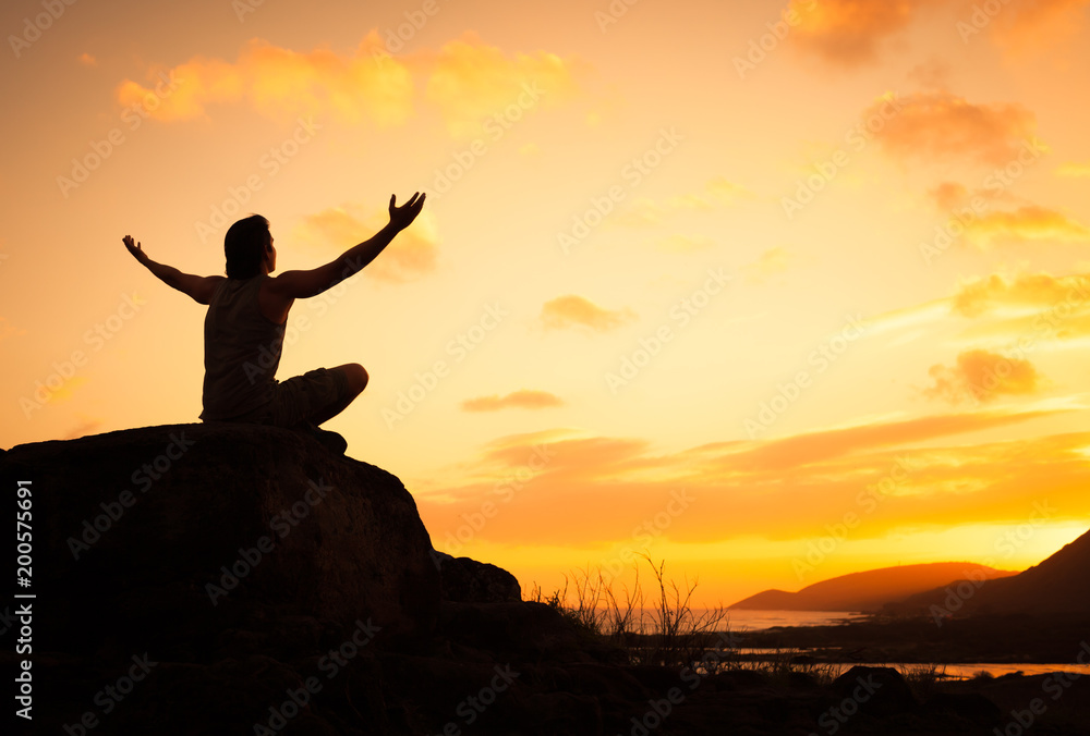 Young man sitting high up on a mountain feeling at peace. 