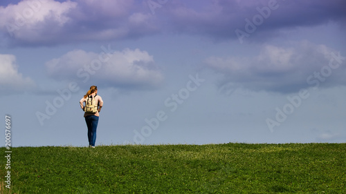 Traveler woman standing at horizon, cloudy sky 