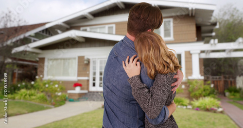 Couple shown from behind embracing and being affectionate outside new home