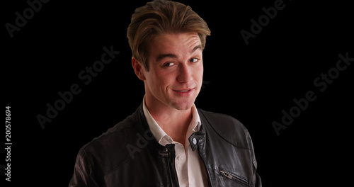 Male in leather jacket winking at camera on black background with copyspace