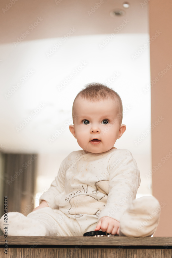 childhood, babyhood and people concept - happy little baby boy or girl sitting at home childhood, babyhood and people concept - happy little baby boy or girl sitting at home