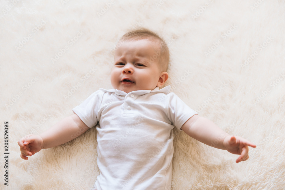 Little beautiful infant baby crying and laying on white background isolated Little beautiful infant baby crying and laying on white background isolated