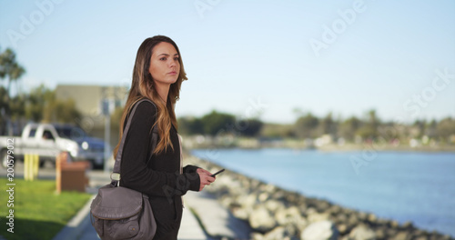Young millennial girl messaging on cell phone by the bay smiling and laughing © rocketclips