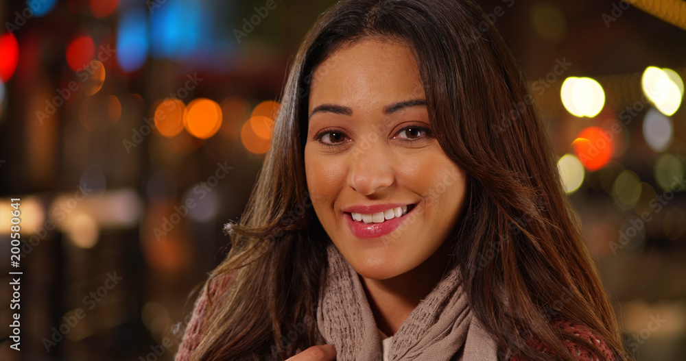 Closeup of beautiful Latina woman touching her hair and smiling warmly at camera Closeup of beautiful Latina woman touching her hair and smiling warmly at camera
