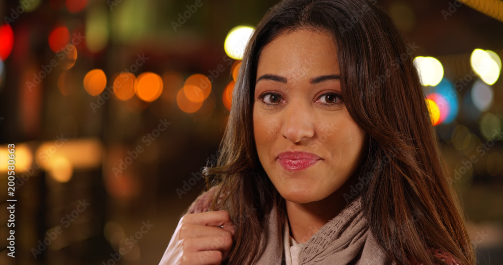 Obraz premium Closeup of beautiful Latina woman touching her hair and smiling warmly at camera