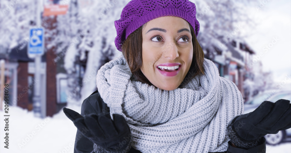 Portrait of joyful Latina female standing in snowy town smiling at camera Portrait of joyful Latina female standing in snowy town smiling at camera