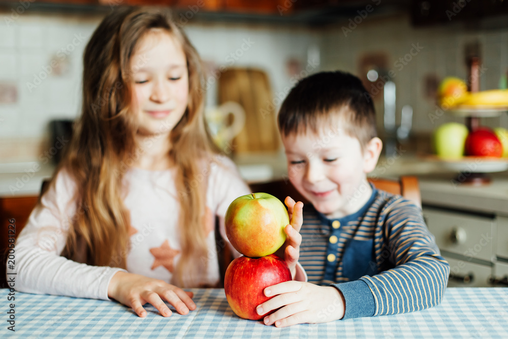 Children eat apples in the kitchen at the morning. Sister and brother have fun. Kids build a tower of apples in the kitchen Children eat apples in the kitchen at the morning. Sister and brother have fun. Kids build a tower of apples in the kitchen
