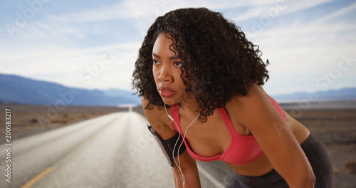 Portrait of strong fit African woman preparing to run on empty highway