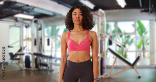 Frontal shot of attractive African-American fitness female standing inside gym