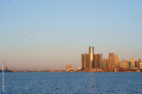 Downtown Detroit view from Belle-Isle during sunrise with view on Bridge to Windsor, Ontario, Canada. The morning sun reflect on GM towers.