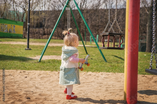 Little baby girl walking near the swings.