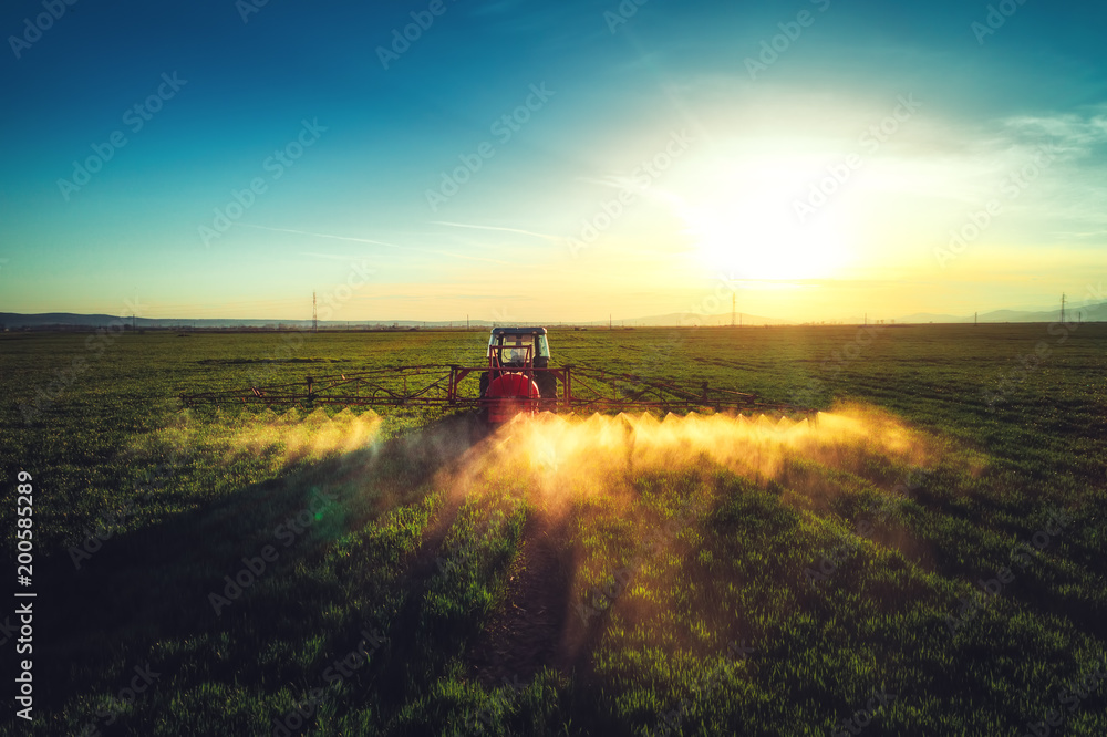 Fototapeta premium Aerial view of farming tractor plowing and spraying on field