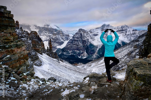 Vacation travel in Banff National Park. Woman hiker meditating at the mountain top with the scenic view of Paradise Valley. Sentinel Pass. Canadian Rockies. Alberta. Canada.