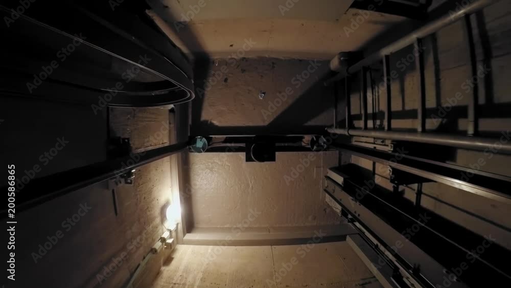 The cabin moves up in an elevator shaft. The view is directed downwards. The camera is moving. The lights in the shaft give the ride its own rhythm. The cabin moves up in an elevator shaft. The view is directed downwards. The camera is moving. The lights in the shaft give the ride its own rhythm.
