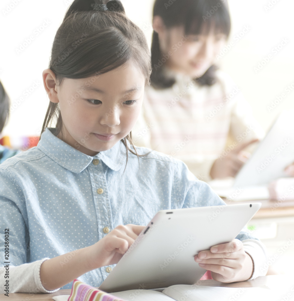 教室でタブレットPCを操作する小学生