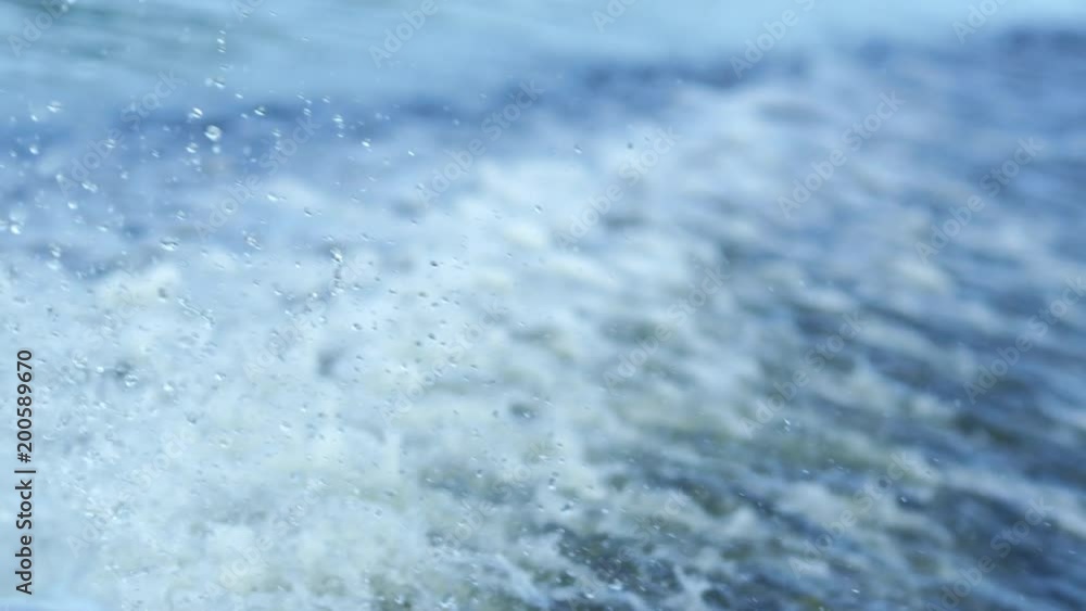 Water splashes on river surface in slow motion. Trail on water surface behind of fast moving motor boat. Water wave background Water splashes on river surface in slow motion. Trail on water surface behind of fast moving motor boat. Water wave background