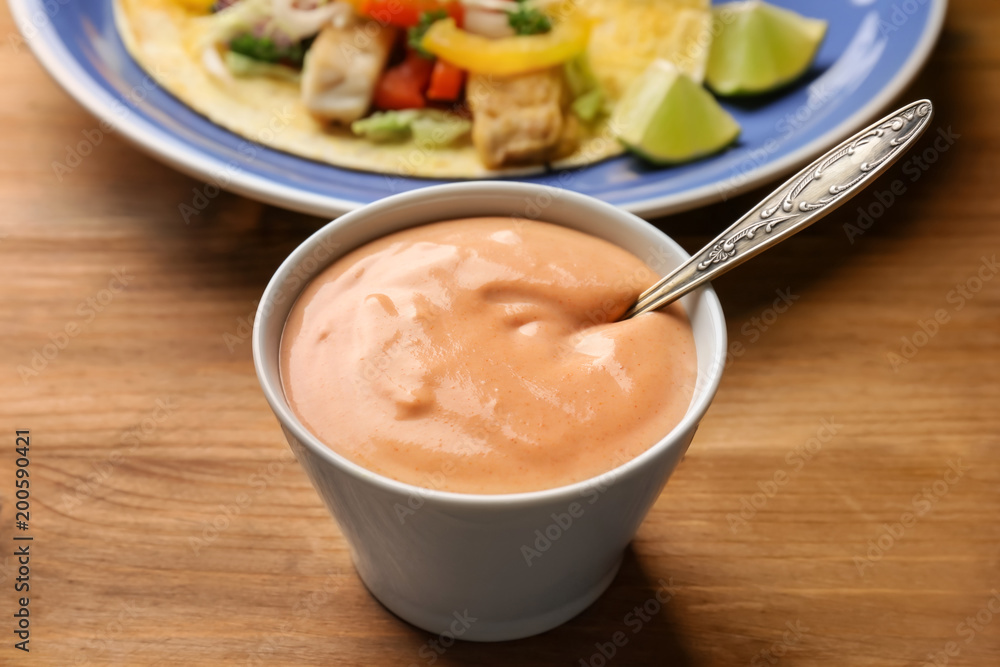 Tasty creamy sauce for fish taco in bowl on wooden table Tasty creamy sauce for fish taco in bowl on wooden table