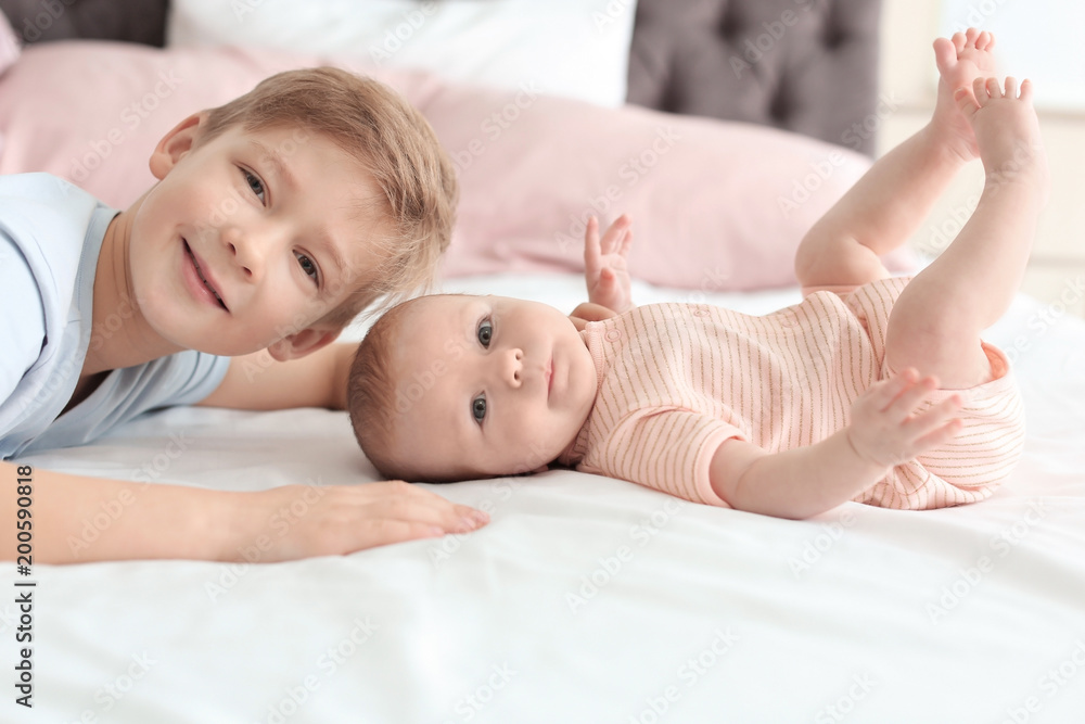 Cute little baby with elder brother lying on bed at home Cute little baby with elder brother lying on bed at home