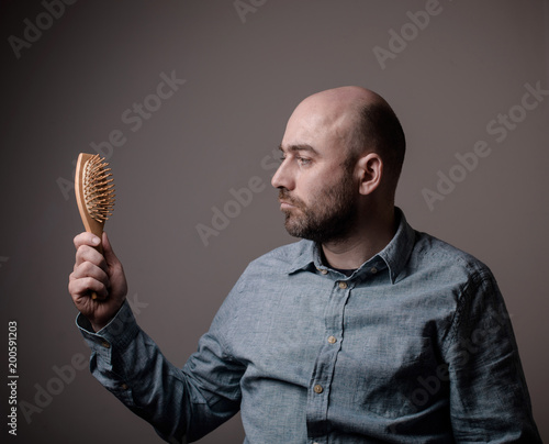 confused bald man with hair brush