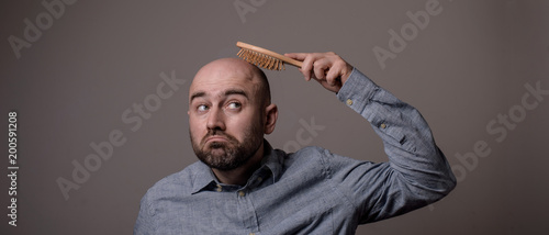 Tableau sur toile confused bald man with hair brush