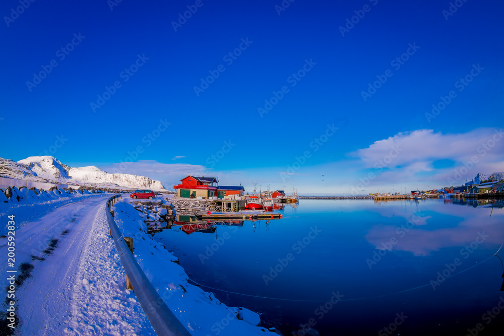 Outdoor view of harbour area with fishing wooden buildings behind viewed from the road, covered with snow in Svolvaer