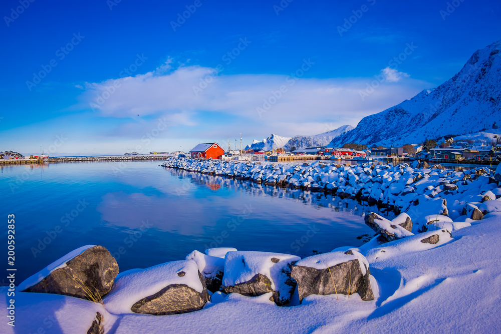 Close up of Rocks covered with snow during a winter station with buildings behind in Svolvaer