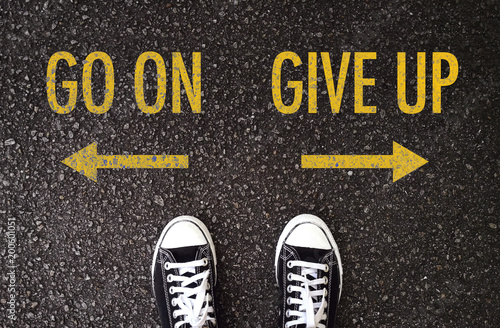 Black shoes standing at the road with go on and give up wording.