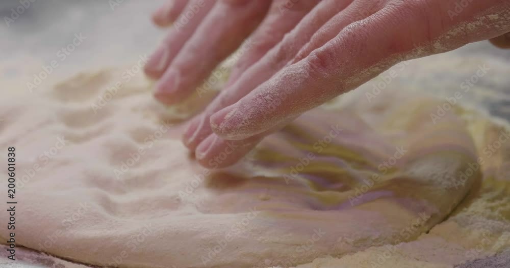 Close up of a pizza chef's hands kneading the dough to prepare a gourmet pizza and spreads the tomato sauce. Concept of: italianità, food, tradition. Close up of a pizza chef's hands kneading the dough to prepare a gourmet pizza and spreads the tomato sauce. Concept of: italianità, food, tradition.