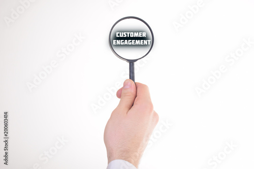 Businessman looking at a magnifying glass word:CUSTOMER ENGAGEMENT