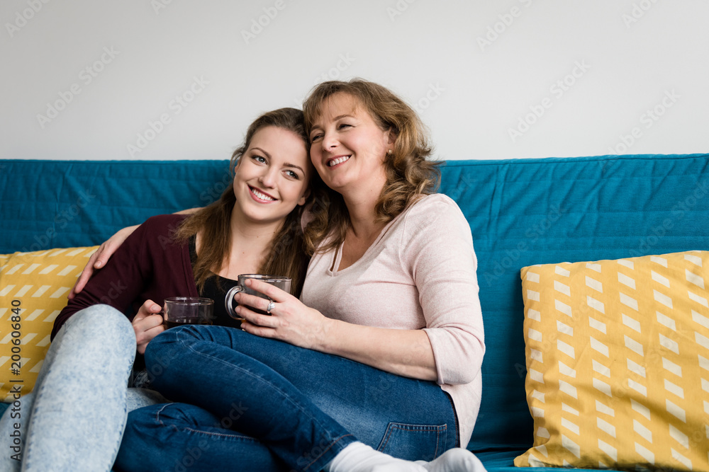 Affectionate mother and daughter sitting on sofa at home Affectionate mother and daughter sitting on sofa at home