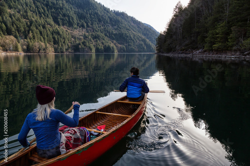 Couple friends canoeing on a wooden canoe during a sunny day. Taken in Harrison River  East of Vancouver  British Columbia  Canada.