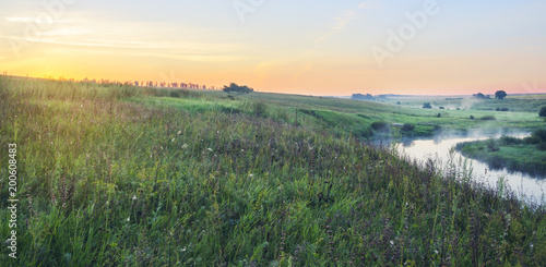 Summer landscape.Green meadows and river at sunrise.Fog over the water. 